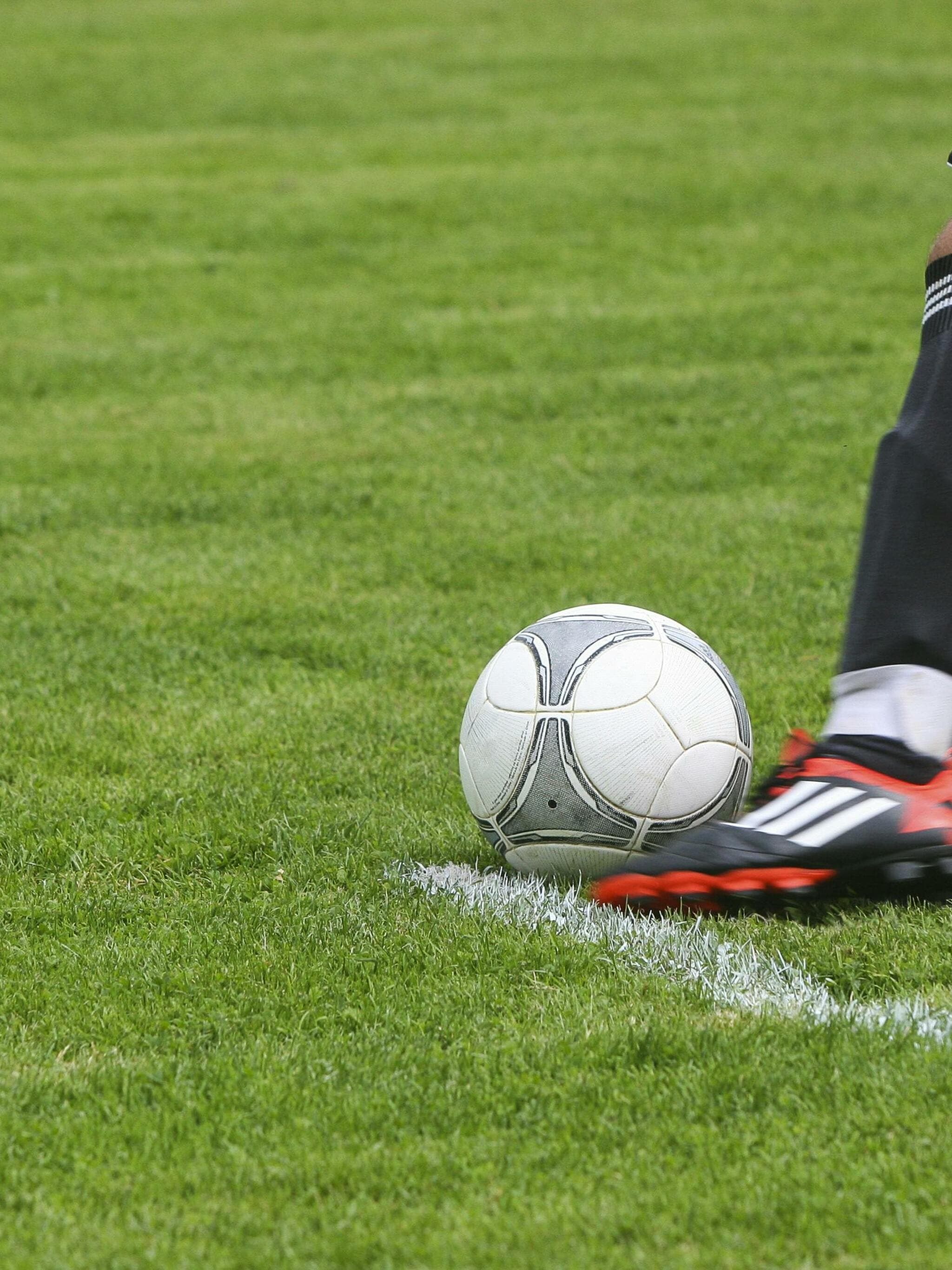 Football player kicking a ball on a grass pitch