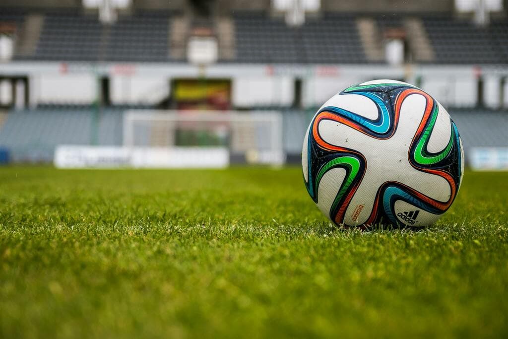 Football on a green pitch in an empty stadium